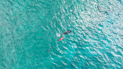 Free diver spearfishing with a red safety buoy in the middle of the ocean sea in Hawaii. Aerial...