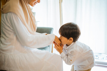 son kissing mother's hand to apologize during Eid celebration at home