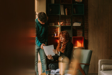 Young stylish businessman explaining something to his redhead female colleague while pointing at her document