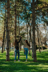 Happy female friends, having fun in the park. Brunette girl standing on one leg and looking back at the camera