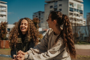 Gorgeous curly haired and brunette girls having fun conversation and laughing