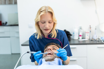 Dentist and patient at medical center. Doctor treats a man teeth with dental drill. Orthodontist and prosthetics appointment. Hygiene and teeth healthy.