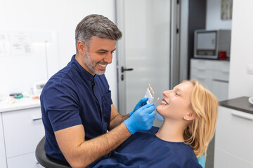 Patient's teeth shade with samples for bleaching treatment.Viewed oral hygiene. Woman at the dentist. Woman in the dental chair dental treatment during surgery.