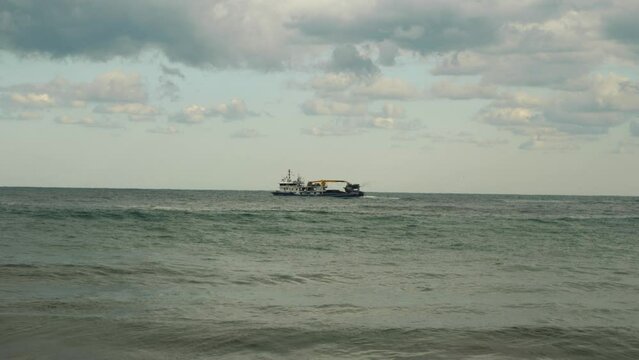 A fishing trawler is bobbing on the waves near the shore. The sea is rough. Bad weather, gloomy morning. Dangerous fishing. Slow motion