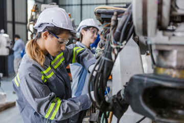 Engineers woman using wrench maintenance robotic arm. Female technician industrial checking robot machine. Futuristic industry production manufacturing.