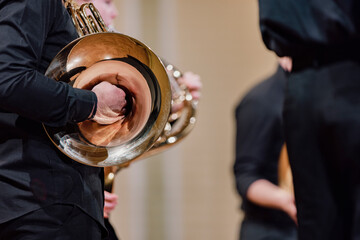 A musician dressed in concert black playing a French horn during a chamber music concert