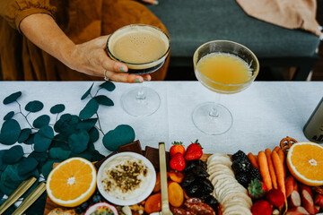 A woman's hand is holding a cocktail on a grazing table.