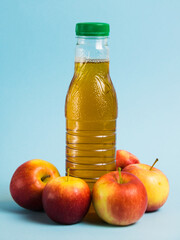 Apple juice in a plastic bottle and red apples on a blue background. Earth day, zero waste and plastic recycling concept.