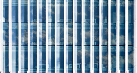 Abstract architecture background - Glass office building facade with mirrored sky with clouds - Architectural pattern.