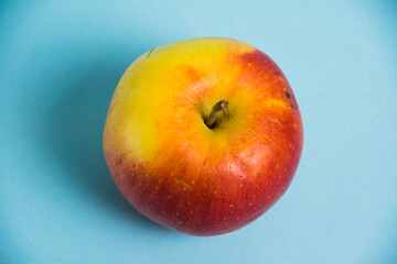 Juicy red yellow apple on a blue background. Concept of earth day, zero waste and plastic recycling.