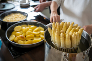 Old Woman cooking white asparagus in the kitchen