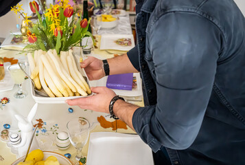 The man serves white asparagus on the table