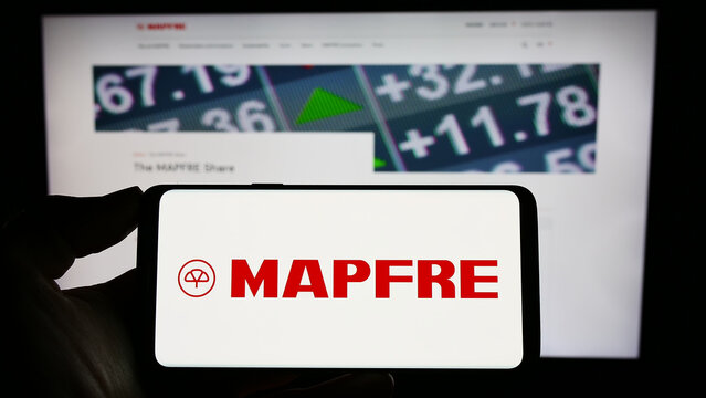 Stuttgart, Germany - 04-01-2023: Person holding mobile phone with logo of Spanish insurance company Mapfre SA on screen in front of business web page. Focus on phone display.