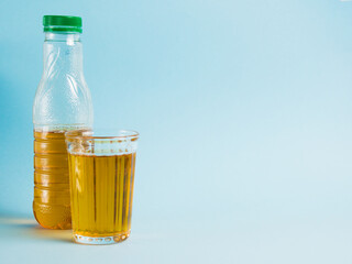 Glass of juice and plastic bottle on blue paper background. Concept of earth day, zero waste and plastic recycling.