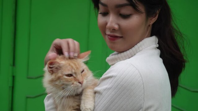 A beautiful Asian woman is carrying her orange Angora cat