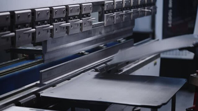 The process of bending steel sheet in production. A worker makes parts with a machine tool and a press