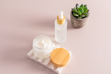 Fototapeta na wymiar an open matte jar with moisturizer on a plaster relief podium and serum in a white matte bottle on a beige background. cosmetic care.