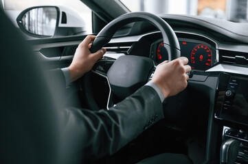 Driving the car. Man in formal business clothes is sitting in the modern automobile