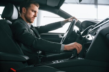 Man in formal business clothes is sitting in the modern automobile