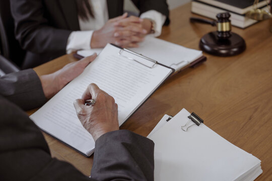 Lawyer preparing to sign a contract reading documents at meeting.