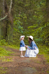 Fototapeta premium Winsome Caucasian Young Mother with Her Daughter Communicating Outdoors in Green Summer Forest.