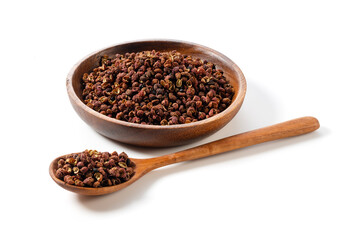 Sichuan pepper, wooden spoon and plate set against a white background.