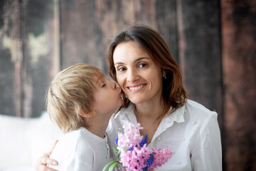 Cute little boy, giving flowers to his mom for Mothers day.