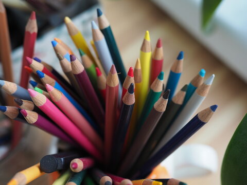 colored pencils are in a glass on the table in a creative mess