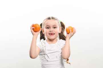 Portrait of a small beautiful girl on a white background with tangerines in her hands.