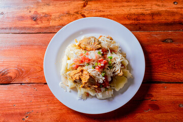 Top view of traditional Chancho dish with Yuca. Nicaraguan pork with yucca served on wooden table