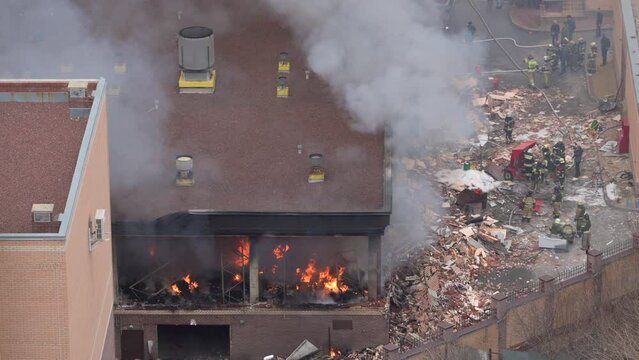 Aerial view of firefighters extinguishing fire in industrial or living area, near high office building after explosion of natural gas