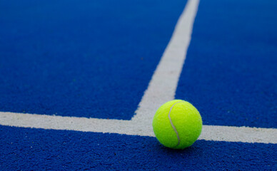 close-up view of a ball on the lines of a blue paddle tennis court, racket sports concept