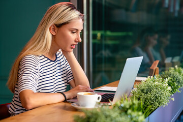 Concentrated at work. Beautiful woman working on laptop in creative office or cafe.