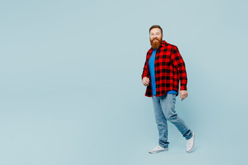 Full body side profile view smiling young redhead bearded man he wear casual clothes walk go stroll...