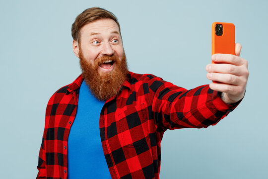 Young redhead bearded man wear casual clothes doing selfie shot on mobile cell phone post photo on social network isolated on plain pastel light blue cyan background studio portrait Lifestyle concept
