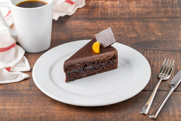 Orange and chocolate cake with cup of coffee on wooden table