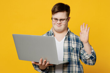 Young smiling IT man with down syndrome wear glasses casual clothes hold use work on laptop pc...