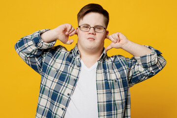 Young man with down syndrome wear glasses casual clothes cover ears with hands fingers do not want...
