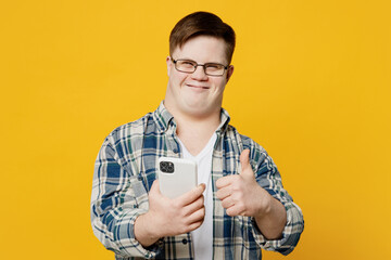 Young happy man with down syndrome wears glasses casual clothes hold in hand use mobile cell phone...