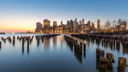 Fototapeta na wymiar New York, USA - April 25, 2022: Lower Manhattan and an old Brooklyn pier at dusk