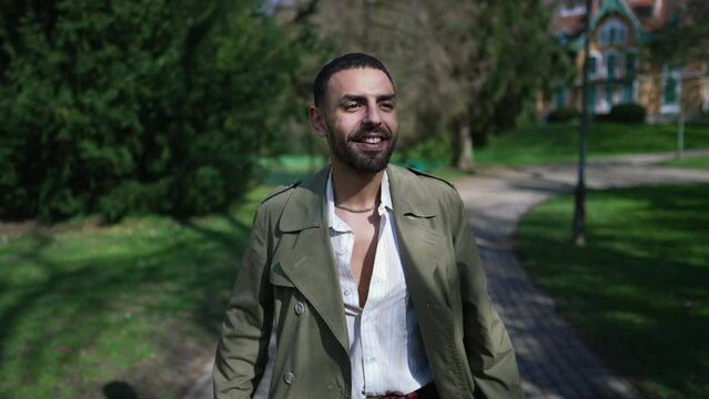 A joyous young Arab man taking a leisurely walk through a sunny park, basking in the warmth of the sun and the beauty of the outdoors