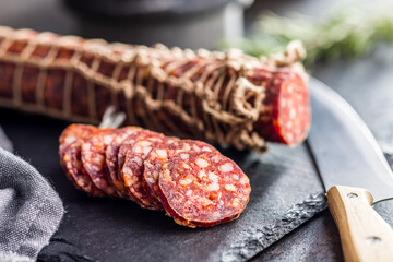 Smoked sausage. Sliced salami on black table.