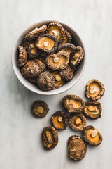 Dried shiitake mushrooms in bowl on kitchen table. Top view.