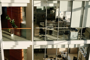 Horizontal image of modern business building with glass walls and workplaces inside