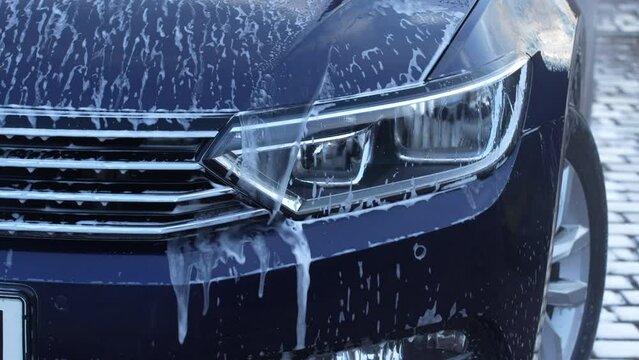 Washing a blue car with high pressure water cleaner, outdoors, close up