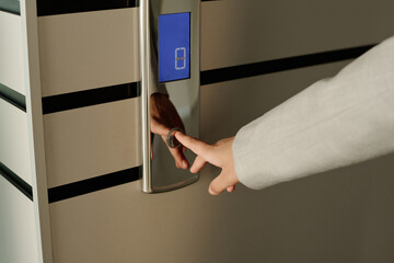 Close-up of businesswoman pushing button of elevator standing in the corridor of office building