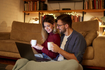 Young couple spending evening at home using laptop