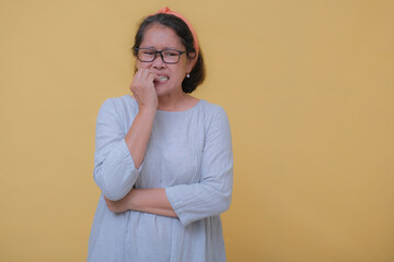 A middle-aged woman biting her nails; nervous expression.