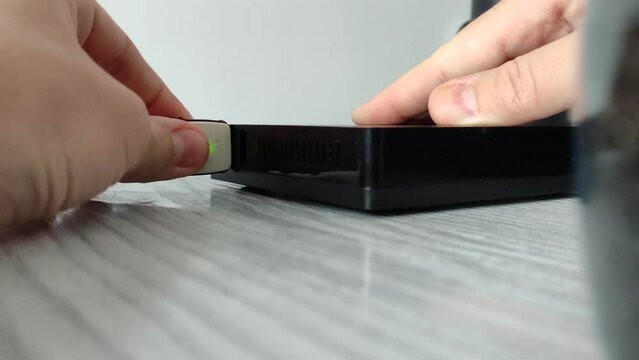 Man connects usb flash drive and cable to mini computer