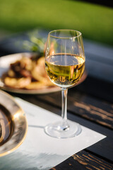 Glass of white wine on wooden table in restaurant. Summer terrace